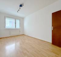 Ein leerer Raum in einer Vierzimmerwohnung mit Holzboden und einem großen Fenster.