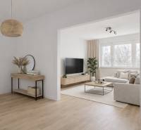 Helles Wohnzimmer mit einer Sitzgarnitur, einem Boden in Holzoptik und einem Fernseher in einer 4-Zimmer-Wohnung.