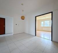 Der Flur mit Fliesen führt in ein helles Wohnzimmer mit Zugang zu einem Boden in Holzoptik.