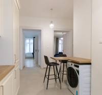 Flur in einer 3-Zimmer-Wohnung mit Waschmaschine, Stühlen und Küchenzeile.