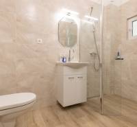 Badezimmer mit Holzboden, Dusche und Schrank in einer 3-Zimmer-Wohnung.