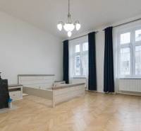 Ein Zimmer mit hellen Möbeln, einem Boden in Holzoptik und großen Fenstern in einer 3-Zimmer-Wohnung.