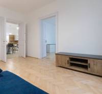 Wohnzimmer einer 3-Zimmer-Wohnung mit einem blauen Sofa und einem Boden in Holzoptik.