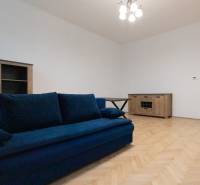 Ein Zimmer mit einem blauen Sofa und Holzboden-Dekor in einer 3-Zimmer-Wohnung.