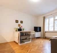 Wohnzimmer in einer 2-Zimmer-Wohnung mit hellen Möbeln und einem Boden in Holzoptik.