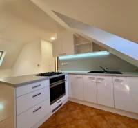 Helle Küche mit Dachfenster, Eckarbeitsplatte und Keramikfliesen in einer Zweizimmerwohnung.