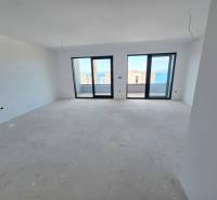 Innenraum einer Ferienwohnung mit Blick durch große Fenster auf das Meer.