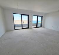 Ein heller Raum in einer Ferienwohnung mit großen Fenstern und Blick auf das Meer.