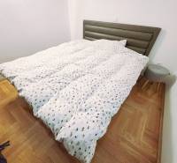 Ferienwohnung mit Bett, Holzboden-Dekor und kleinem Nachttisch.