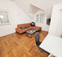 Ferienwohnung mit orangefarbenem Sofa und Boden in Holzoptik.