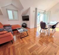 Ferienwohnung mit orangefarbenem Sofa, Esstisch und Holzboden.