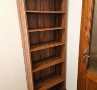 Ein Regal mit fünf Regalböden neben einer Holztür und einem Boden mit Holzdekor.