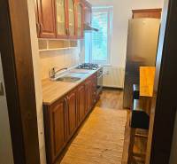 Küche in einer 3-Zimmer-Wohnung mit Holzelementen und hellem Teppich.