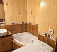 Badezimmer mit Eckbadewanne, Waschmaschine und Waschbecken in einer 3-Zimmer-Wohnung.