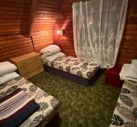 Ein Zimmer in einer Hütte mit Holzverkleidung, drei Betten und einer Kommode.