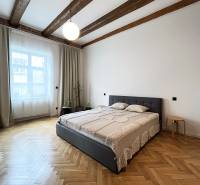 Helles Schlafzimmer mit Holzbalken, bequemem Bett und Parkettboden in der Vajnorská-Straße.
