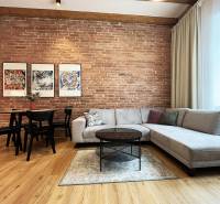 Wohnzimmer mit Ziegelwand, Sofa, Tisch und Bildern; heller Raum in der Vajnorská-Straße, Bratislava.