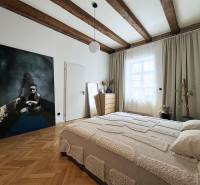Helles Schlafzimmer mit Holzbalkendecke, Bild an der Wand und dezenter Dekoration.