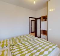 Schlafzimmer in einer 4-Zimmer-Wohnung mit Bett, grüner Bettwäsche und Einbauschrank.