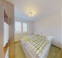 Schlafzimmer in einer 4-Zimmer-Wohnung mit Bett, Einbauschrank und Boden mit Holzdekor.