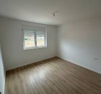 Ein Zimmer in einer 3-Zimmer-Wohnung mit einem Boden in Holzoptik und weißen Wänden.