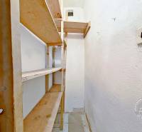 Ein schmaler Abstellraum mit Holzregalen in einer 3-Zimmer-Wohnung, weiße Wände.