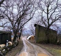 Der schlammige Weg mit Pfützen führt an den Scheunen in Krásnohorské Podhradie auf der Mierová vorbei. Grundstücke - Wohnen.