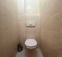 Toilette mit weißen Fliesen und eingebauter Toilette in einer 3-Zimmer-Wohnung.