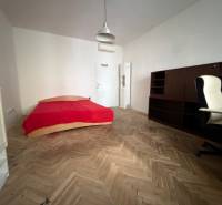 Ein Zimmer mit einem Bett, einem Schreibtisch und einem Boden mit Holzdekor in einer 3-Zimmer-Wohnung.