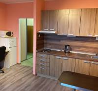 Einzimmerwohnung mit Küchenzeile, Tisch, Stuhl und Boden in Holzoptik.