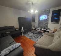 Wohnzimmer mit zwei Sofas, Fernseher an der Wand, Boden mit Holzdekor.