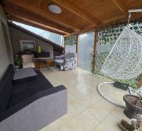 Terrasse in einem Einfamilienhaus in Hont mit Schaukel, Sofa und Korbsessel.