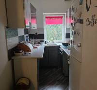 Eine schmale Küche mit schwarz-weißen Schränken und einem großen weißen Kühlschrank in einem Einfamilienhaus.