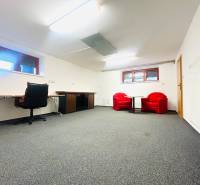 Das Büro im Einfamilienhaus hat einen Teppich, einen Schreibtisch und rote Sessel.