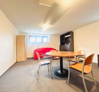 Büro in einem Einfamilienhaus mit Fenstern, Tisch, Stühlen, Sofa und Schrank.