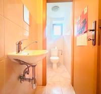 Badezimmer in einem Einfamilienhaus mit Waschbecken, Toilette und hellen Fliesen an den Wänden.