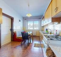 Eine Küche mit einem Boden in Holzoptik, hellen Möbeln und einem Esstisch in einem Einfamilienhaus.