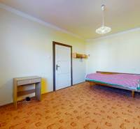 Ein Zimmer in einem Einfamilienhaus mit einem Bett, einem Tisch und einem gemusterten Teppich.