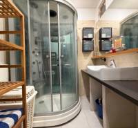 Badezimmer mit Duschkabine und Waschbecken mit Holzdekor, 3-Zimmer-Wohnung.