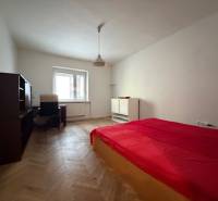 Schlafzimmer in einer 3-Zimmer-Wohnung mit Bett, Schreibtisch und Holzboden.