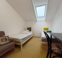 Ein Zimmer in einem Einfamilienhaus mit Dachfenster, zwei Betten und einem Sessel.