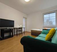 Wohnzimmer in einem Einfamilienhaus mit Sofa, Fernseher, Tisch und Holzboden.