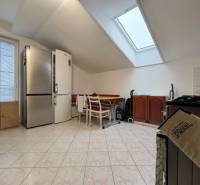 Küche in einem Einfamilienhaus mit schräger Decke, großem Kühlschrank und Esstisch.