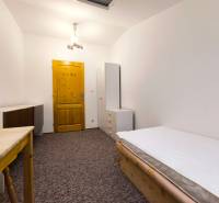 Ein Zimmer in einem Einfamilienhaus mit einem Bett, einem Schrank und einem Tisch, ergänzt durch weiße Beleuchtung und Teppichboden.