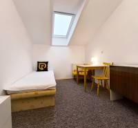 Einfaches Zimmer mit Einzelbett, Tisch und Stühlen in einem Einfamilienhaus.