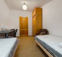 Ein Zimmer in einem Einfamilienhaus mit Betten, einem Tisch, einem Schrank und einem Stuhl.