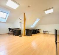 Büros mit Holzboden, Tischen, Stühlen und Dachfenstern.
