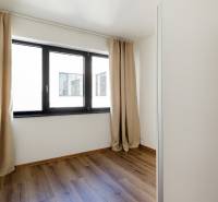 Ein Zimmer in einer 3-Zimmer-Wohnung mit einem Boden in Holzoptik und einem Fenster mit Vorhang.