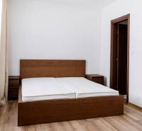 Schlafzimmer in einer 3-Zimmer-Wohnung mit einem Bett aus dunklem Holz und einem Boden mit Holzdekor.