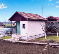 Eine Hütte in Partizánske mit einem gepflegten Garten, einem Gewächshaus und einer Anbaufläche.